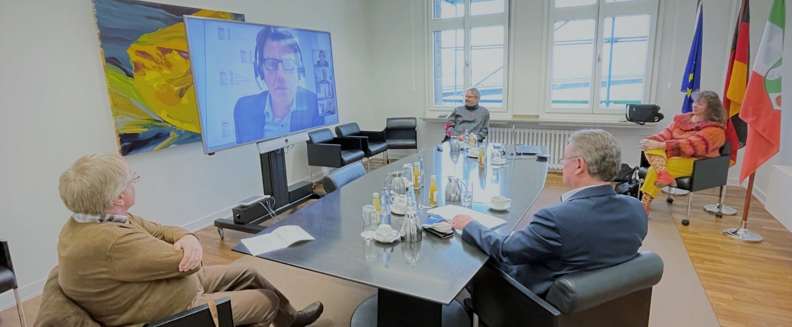 Staatsekretärin Milz nimmt mit 3 Herren an einer Videokonferenz teil. Auf dem Bildschirm sieht man einen weiteren Herrn.