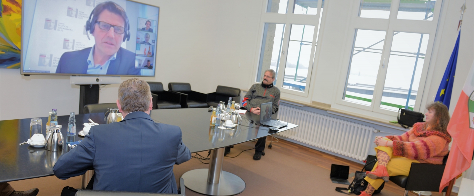 Staatssekretärin Milz nimmt mit 3 Herren in einem Besprechungsraum an einer Videokonferenz teil.