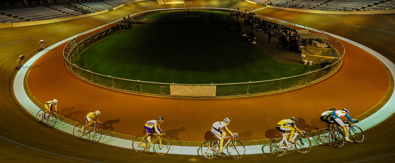 Acht Rennradsportler fahren im Kreis auf der Radbahn des Kölner Radstadions im Sportpark Müngersdorf.