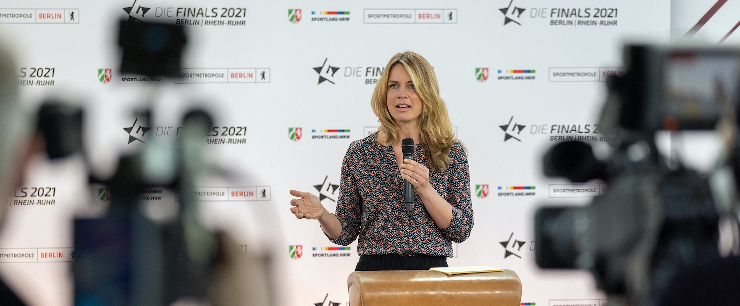 Eine Frau mit einem Mikrofon bei einer Pressekonferenz.