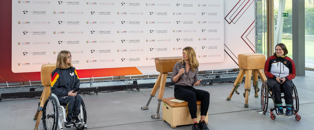 Zwei Rollstuhlfahrerinnen bei der Pressekonferenz vor der Pressetafel Die Finals 2021