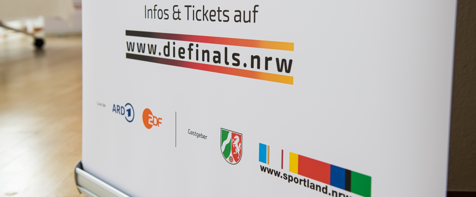 Weißer Roll-up mit Schriftzug www.diefinsals.nrw, NRW-Wappen und Logos von ARD, ZDF und Sportland.NRW.
