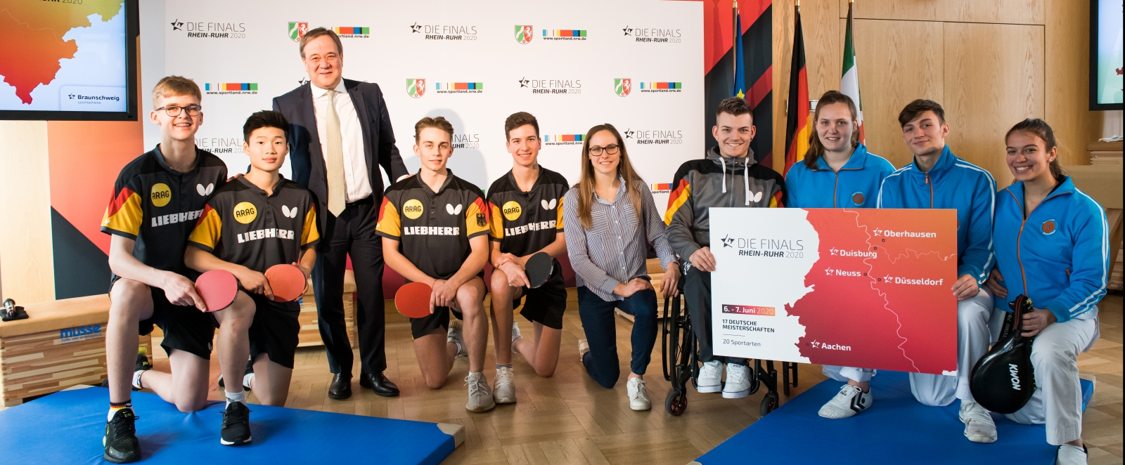 Ministerpräsident Armin Laschet steht mit einem Tischtennisspieler-Team zusammen für ein Portraitbild.