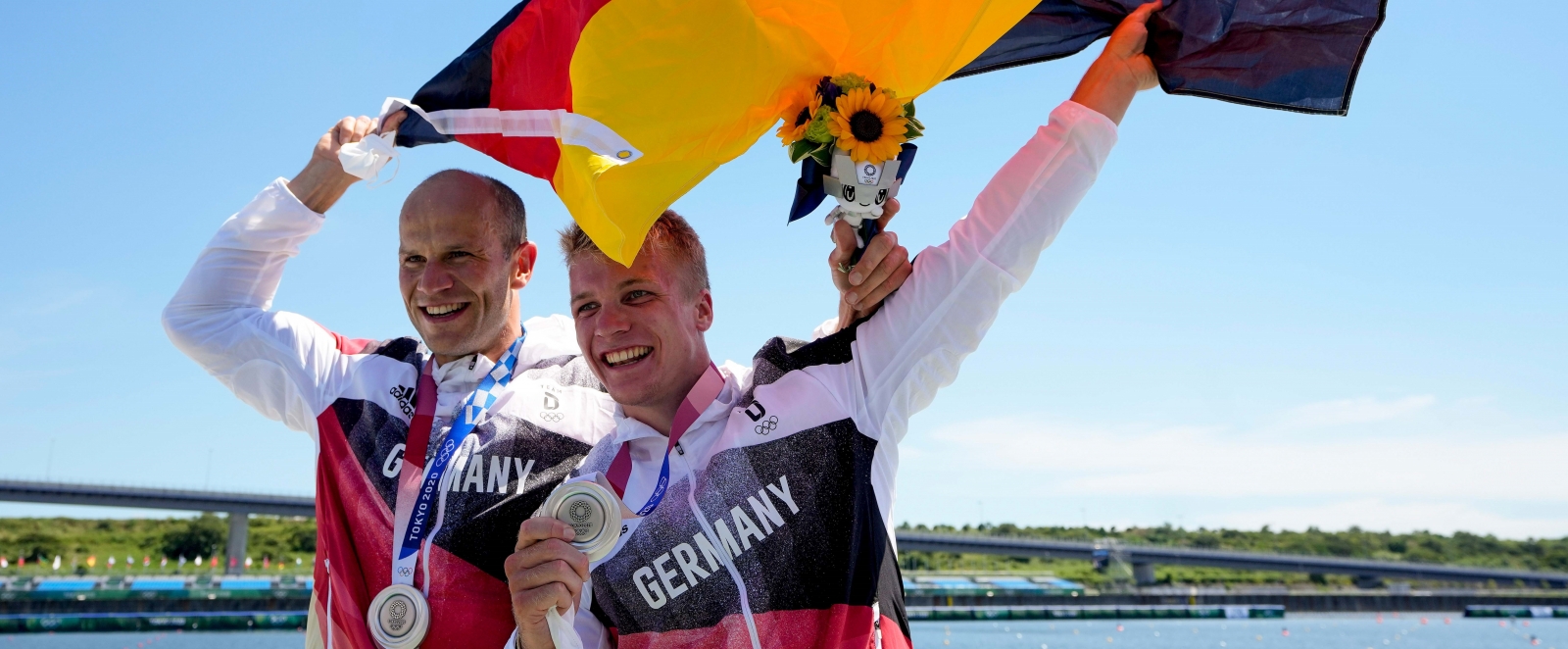 Hoff und Schopf mit Deutschland Fahne und Silbermedaille vor blauem Himmel