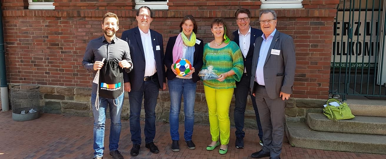 Staatssekretärin Andrea MIlz mit Mitgliedern des Solinger Sportbund e.V. vor einer Hauswand.