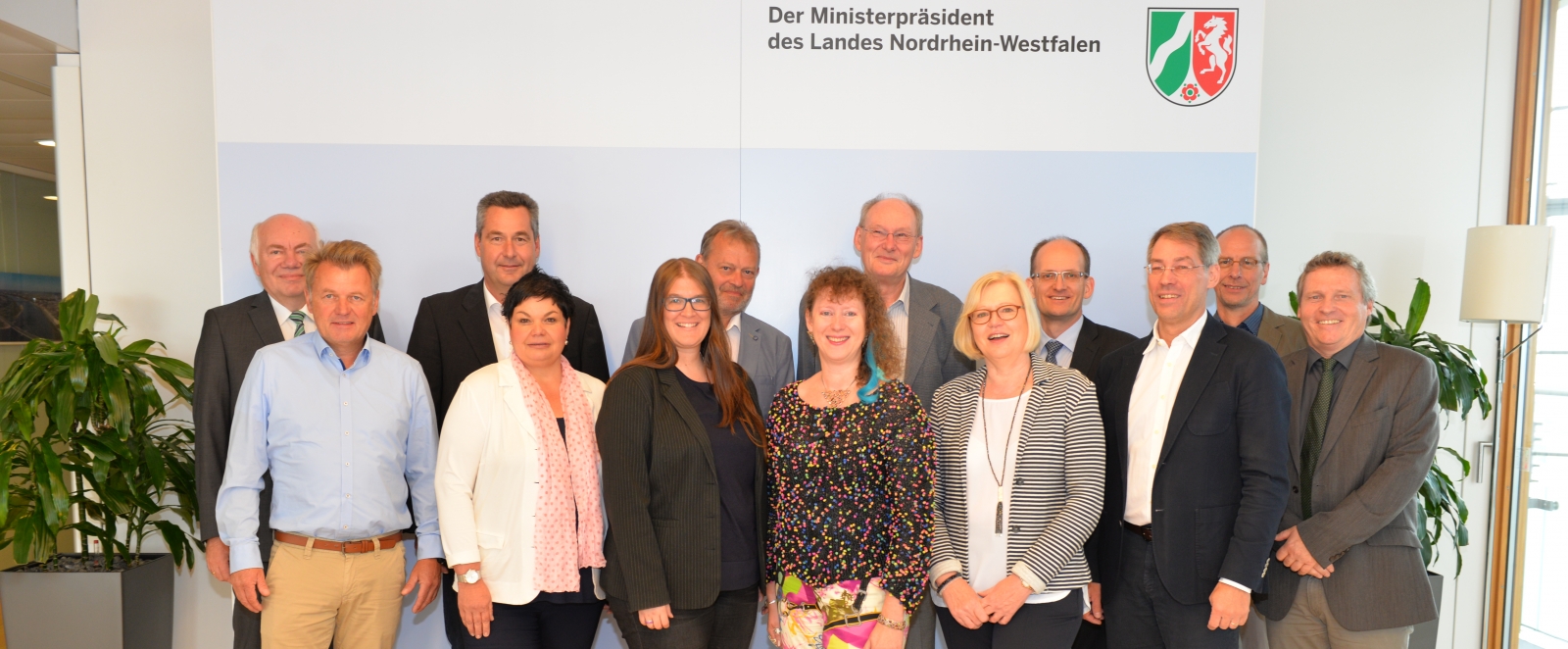 Staatssekretärin Milz steht mit den Teilnehmern des Arbeitstreffen vor einer weißen Wand, über Ihnen auf der Wand befindet sich ein NRW-Logo.
