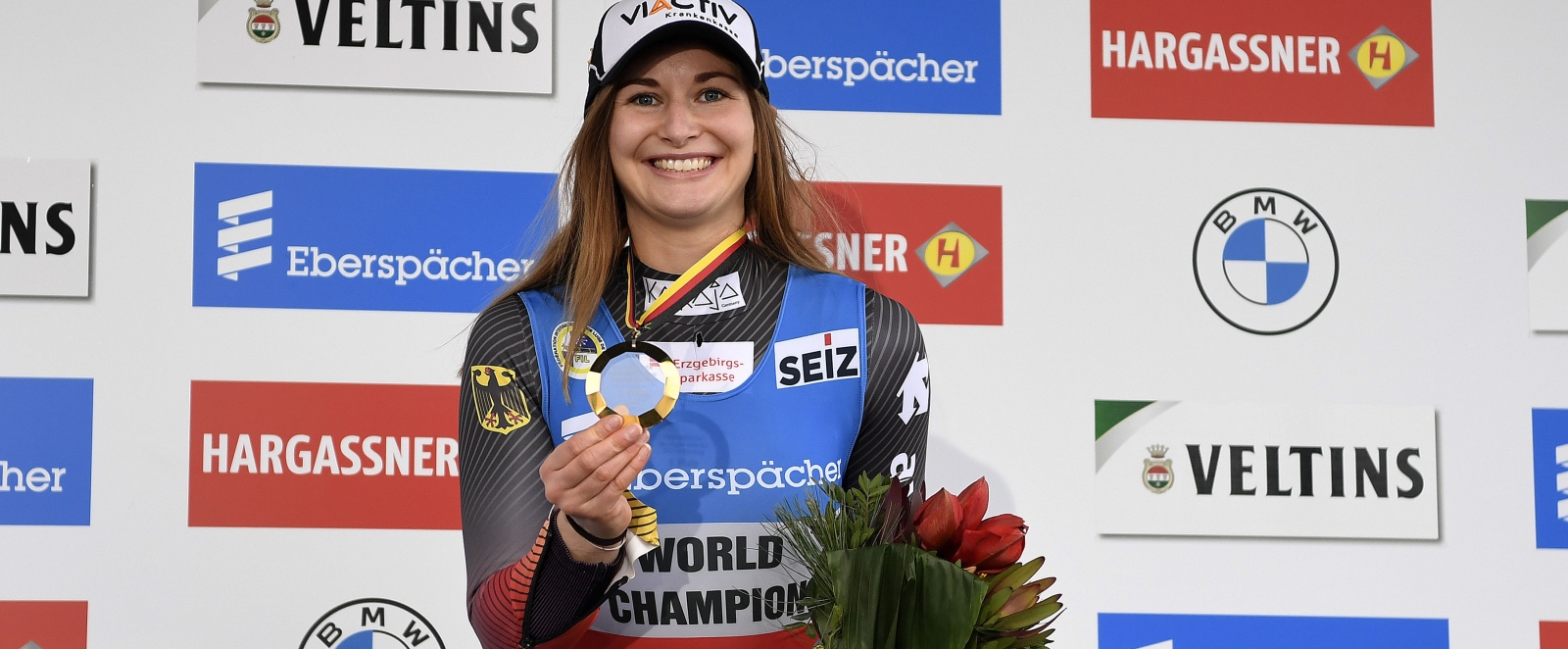 Julia Taubitz präsentiert lachend ihre Medaille