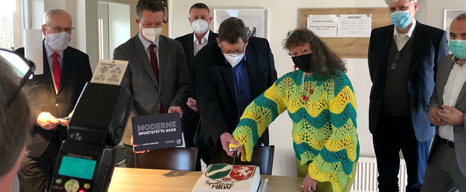 Staatssekretärin Milz schneidet mit einem Herrn eine Nordrhein-Westfalen-Torte an.