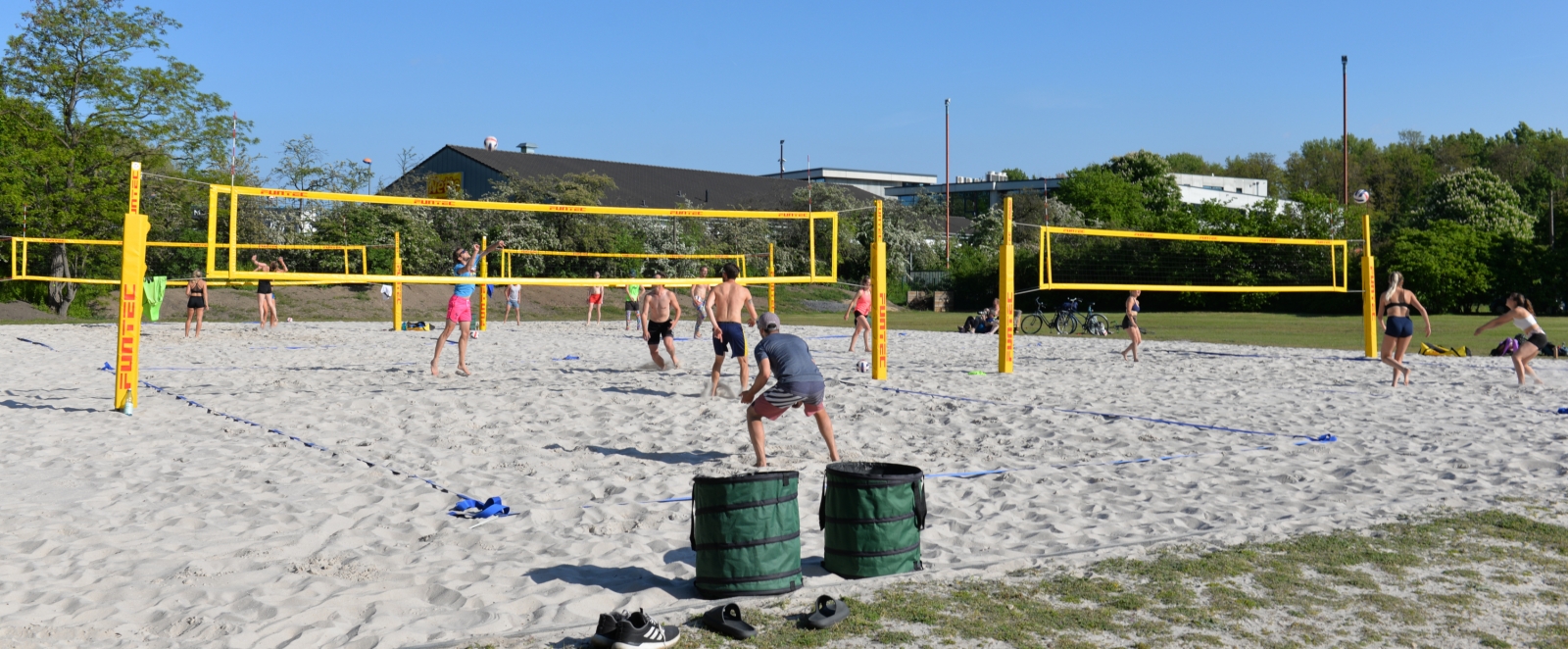 Mehrere Menschen spielen auf Beachvolleyballplätzen.