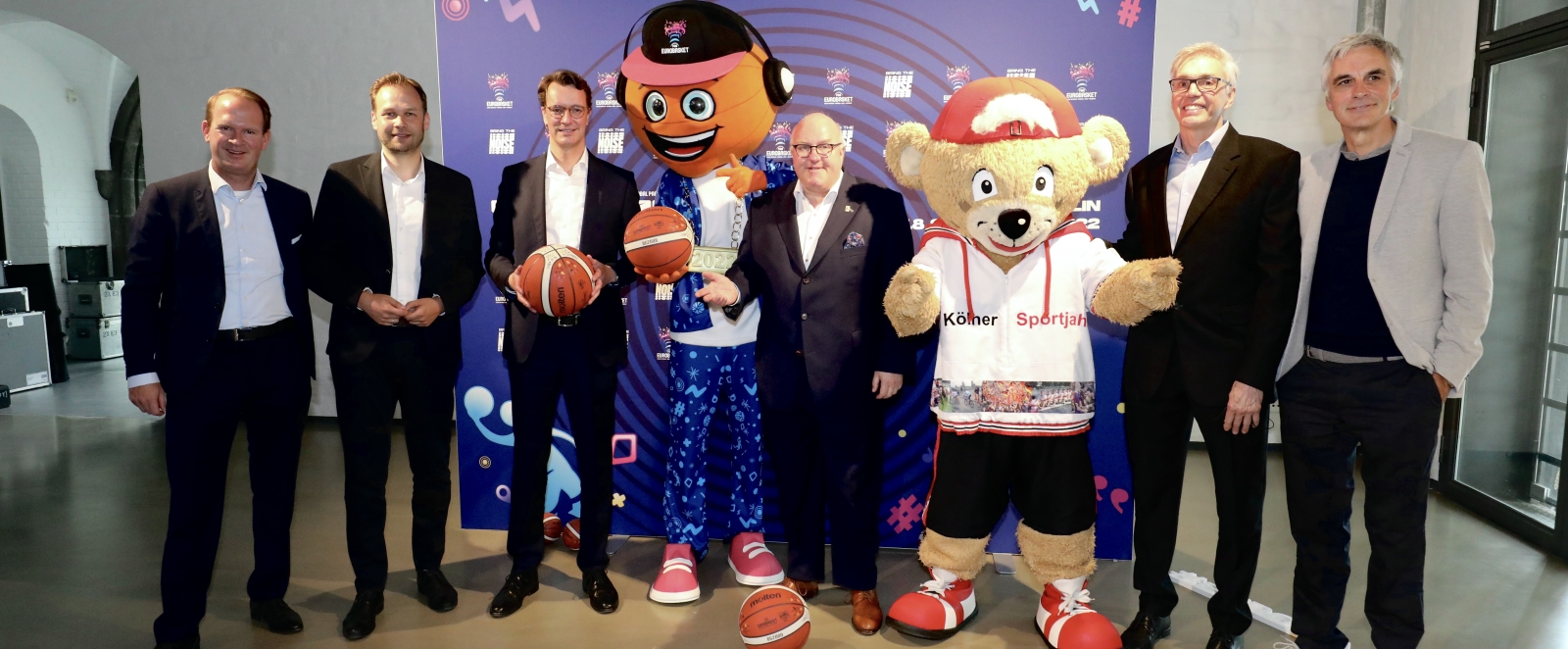 Gruppenfoto u.a. mit Hendrik Wüst und Maskottchen