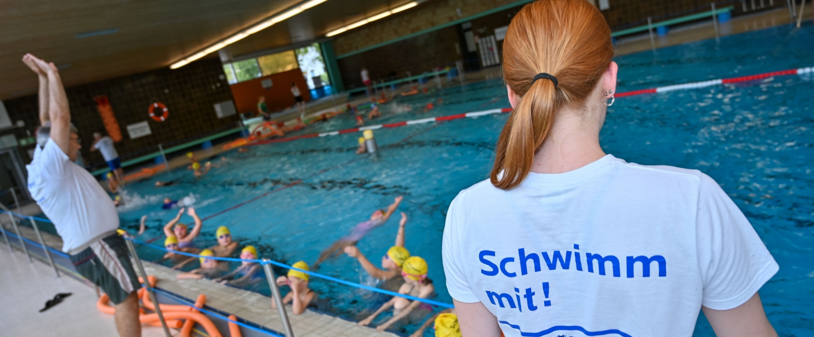 Schwimmlehrer mit Schülern im Hallenbad