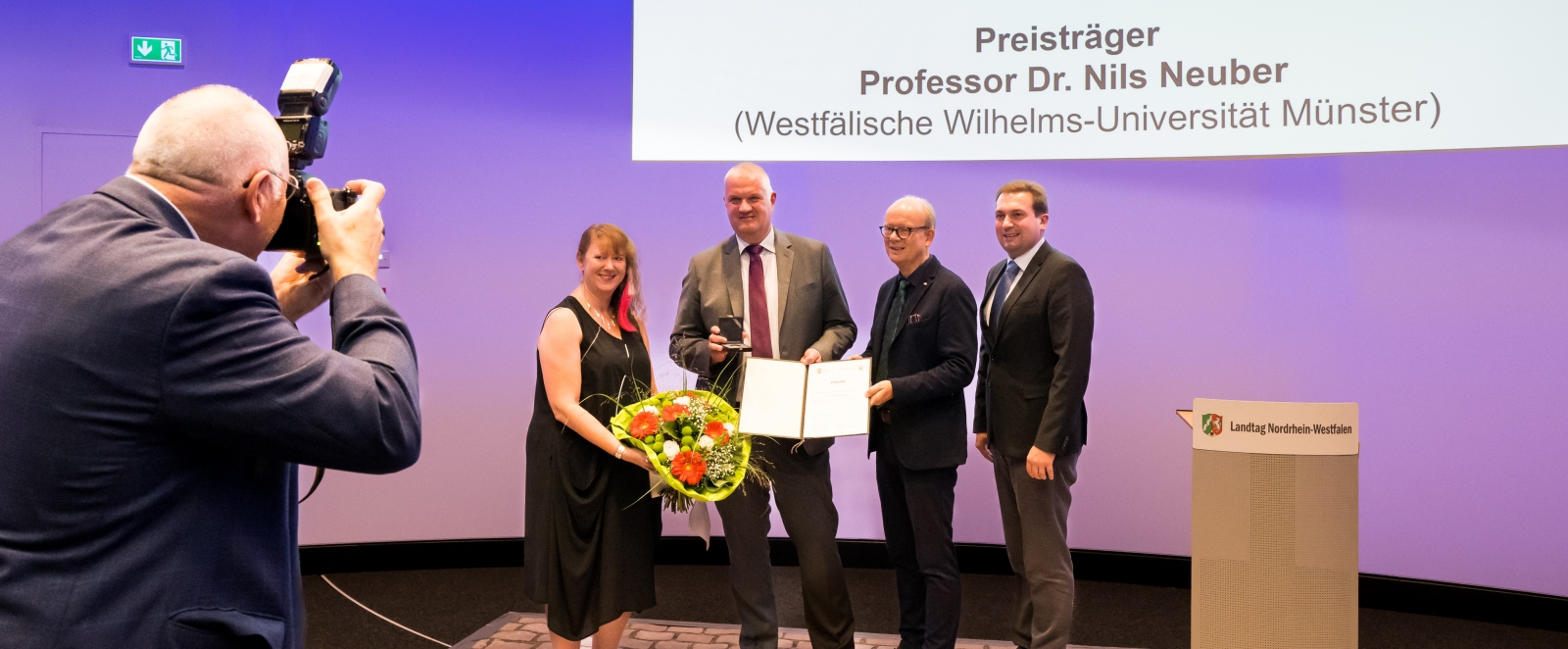 Staatssekretärin Milz überreicht einen Blumenstrauß an den Preisträger Prof. Dr. Nils Neuber.