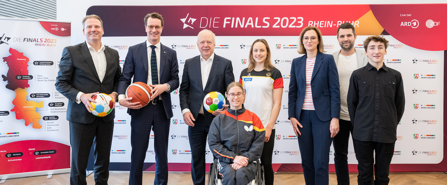 Mehrere Personen vor Sponsorenwand der Finals 2023