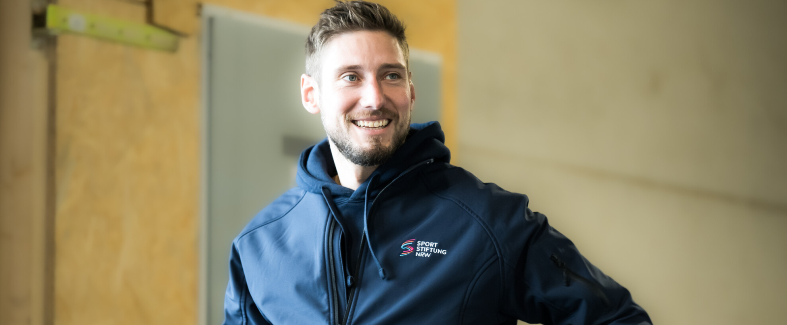 Portraitfoto Max Hartung mit blauer Sportjacke 