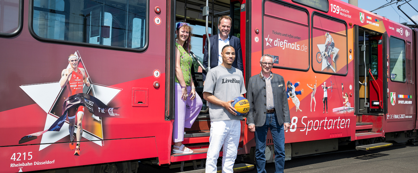 Personen vor einer für die Finals 2023 gebrandeten Straßenbahn