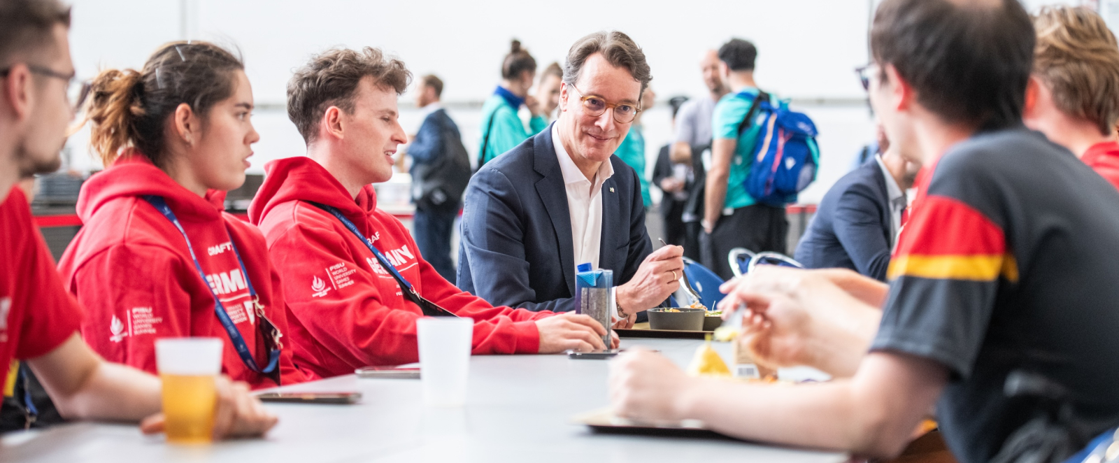 Ministerpräsident Wüst mit Teilnehmenden an einem Tisch