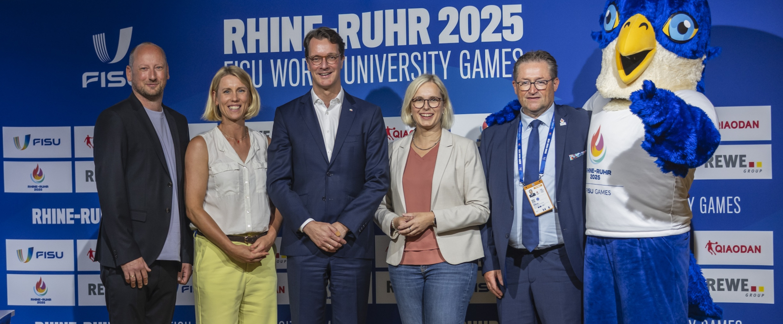 Ministerpräsident Wüst mit weiteren Personen auf Bühne bei Eröffnungspressekonferenz