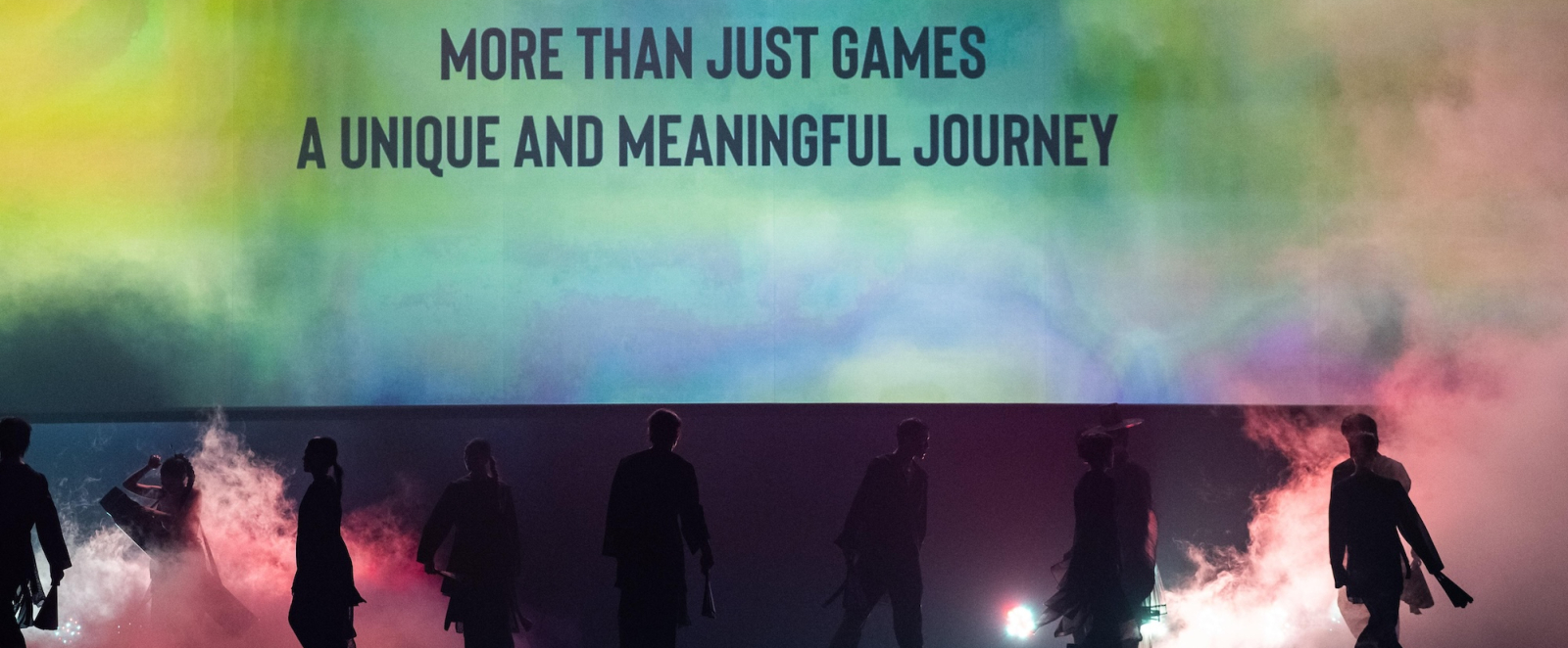 Bühnenhintergrund mit Schriftzug: "More than Just Games, a unique and meaningful journey"
