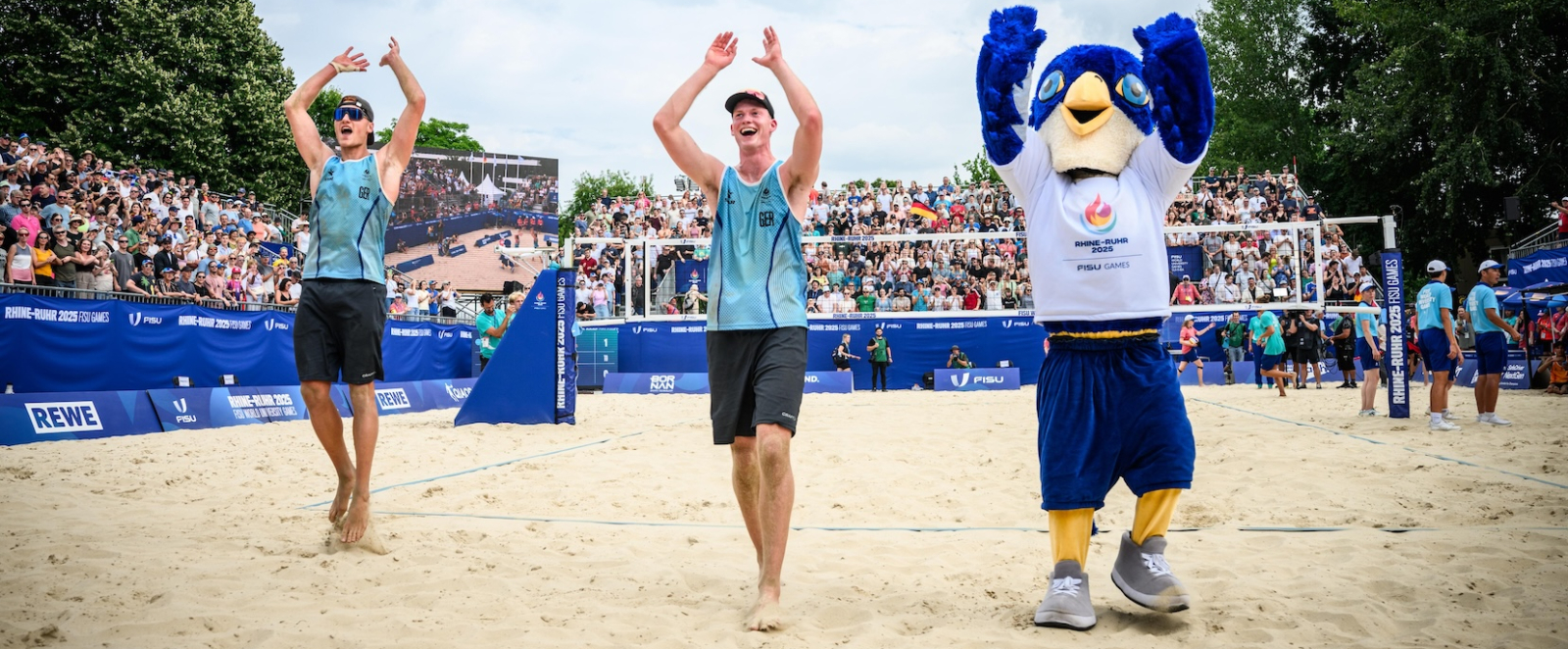 Zwei Beachvolleyballer auf dem Court mit dem Maskottchen