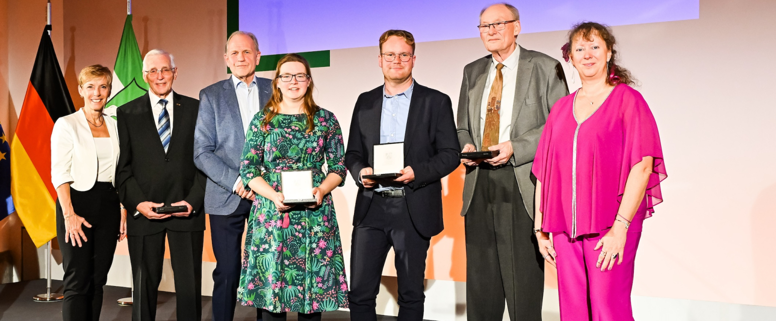Geehrte bei der Verleihung der Sportplakette auf einer Bühne mit Andrea Milz
