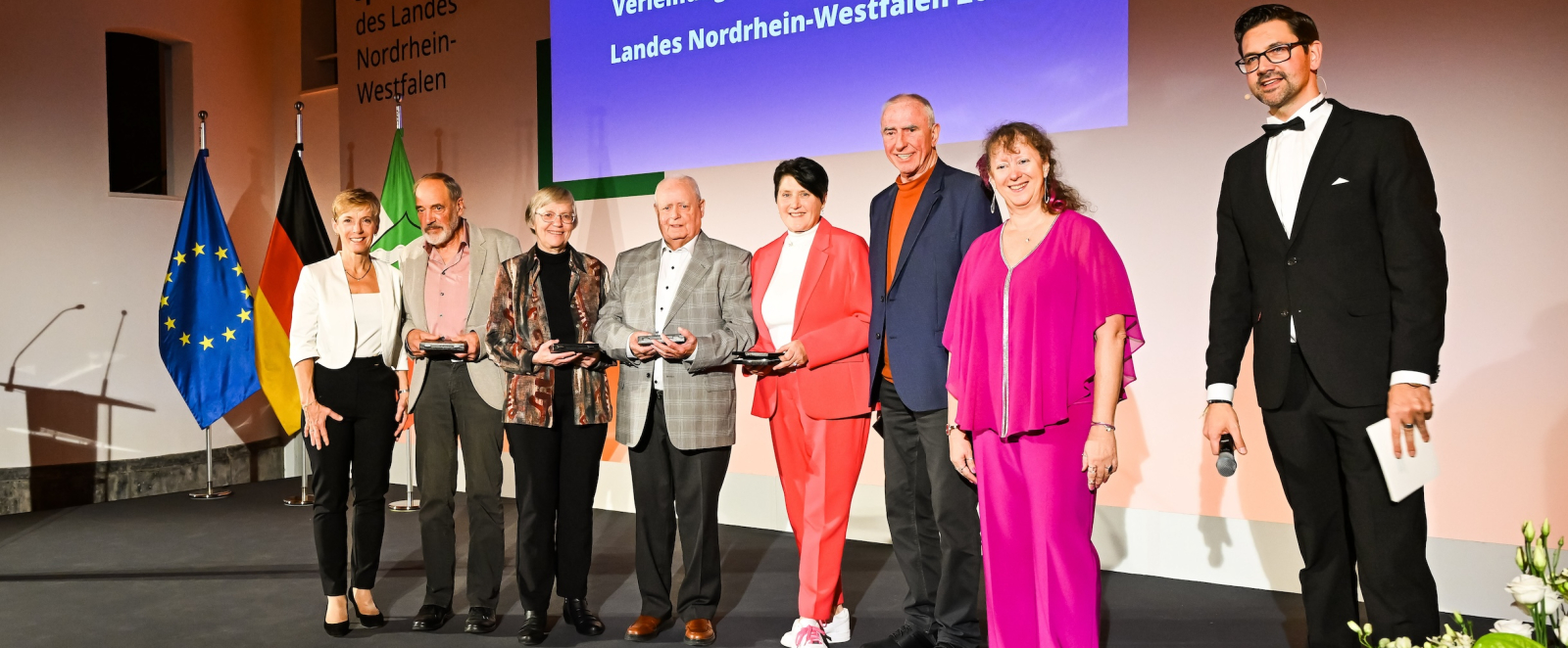 Geehrte bei der Verleihung der Sportplakette auf einer Bühne mit Andrea Milz
