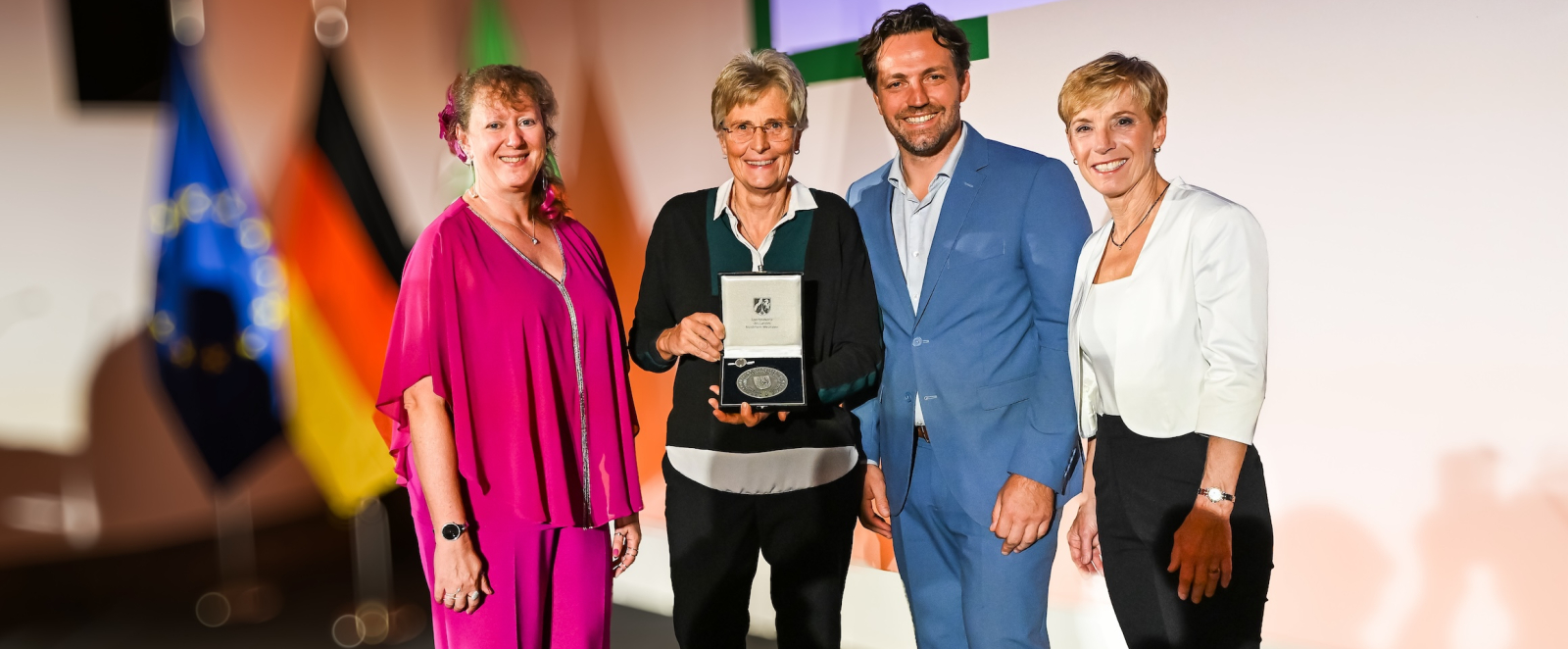 Geehrte bei der Verleihung der Sportplakette auf einer Bühne mit Andrea Milz