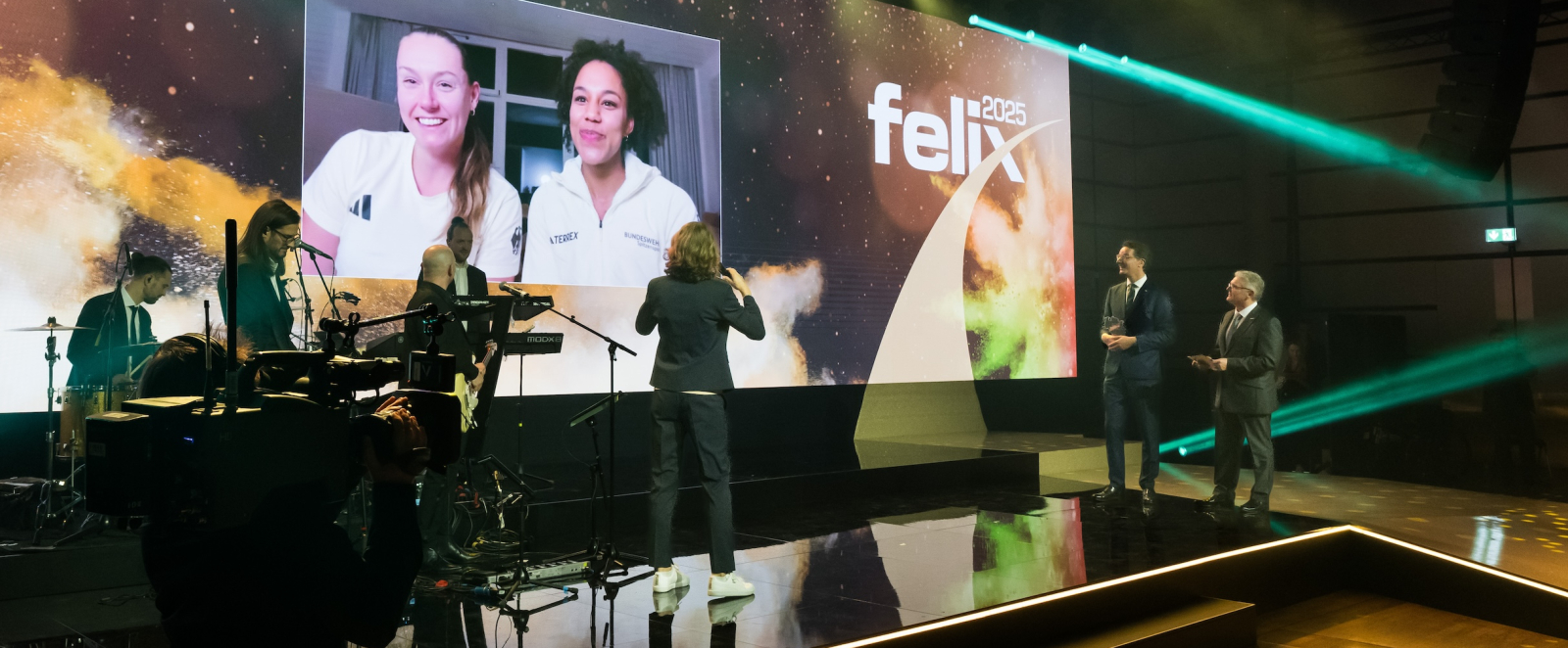 Preisübergabe auf der Bühne mit großem Bildschirm im Hintergrund