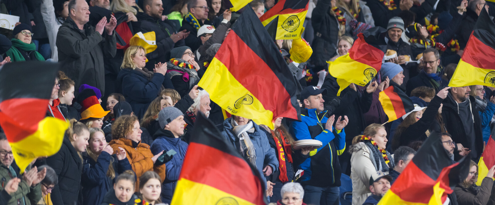 Zuschauer auf einer Tribüne, die Deutschland-Flaggen schwenken
