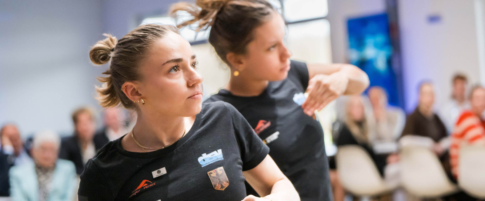 Zwei junge Frauen in schwarzen Shirts führen etwas auf der Jubiläumsfeier vor