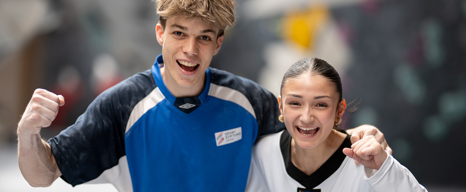 Sportler in blauem Shirt, Sportlerin in weißem Shirt, beide ballen die Faust