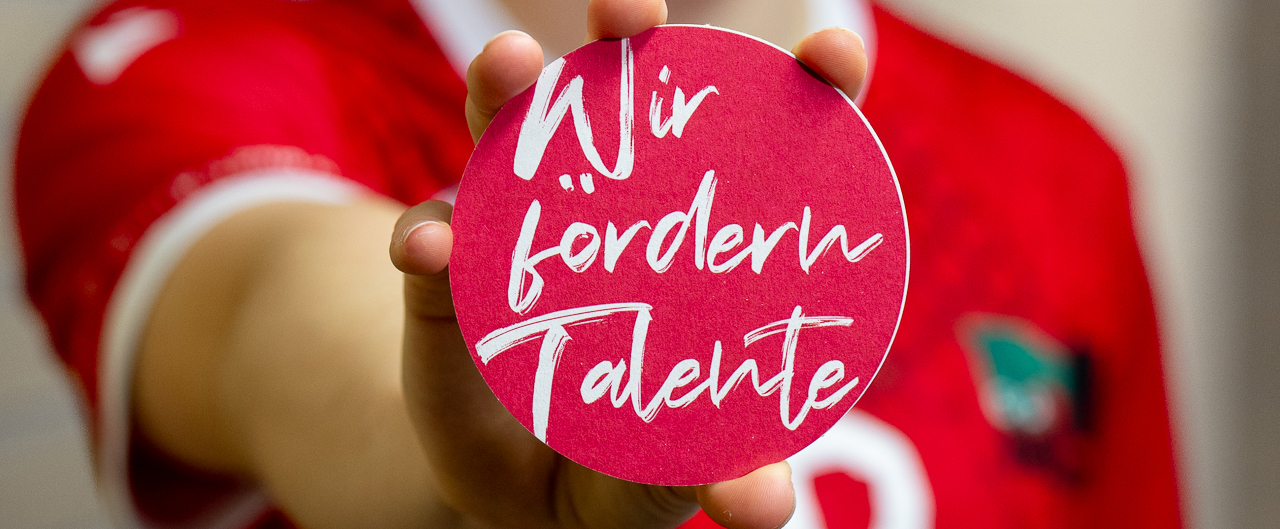 Junge Athletin in rotem Shirt hält Plakette in die Kamera