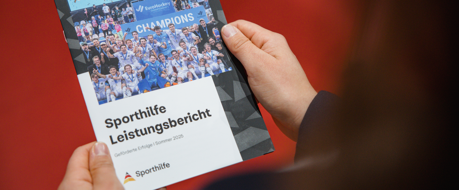 jemand hält einen ausgedruckten Sporthilfe-Bericht in den Händen