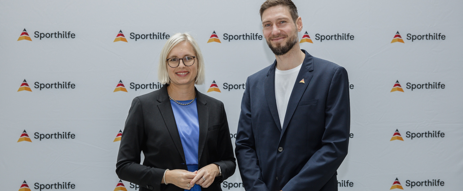 Dr. Christiane Schenderlein und Max Hartung vor einem Sporthilfe-Screen
