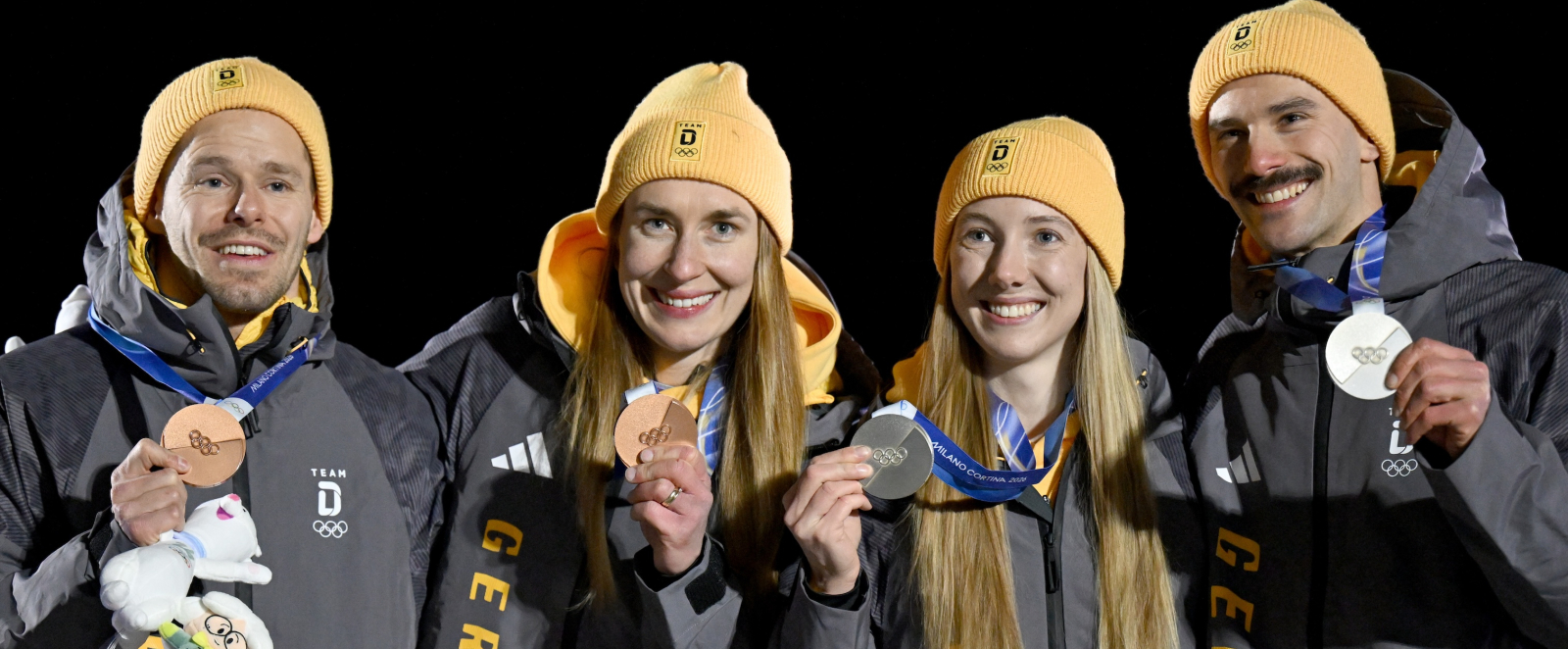 Vier Skeletonis bei der Siegerehrung vor dunklem Hintergrund