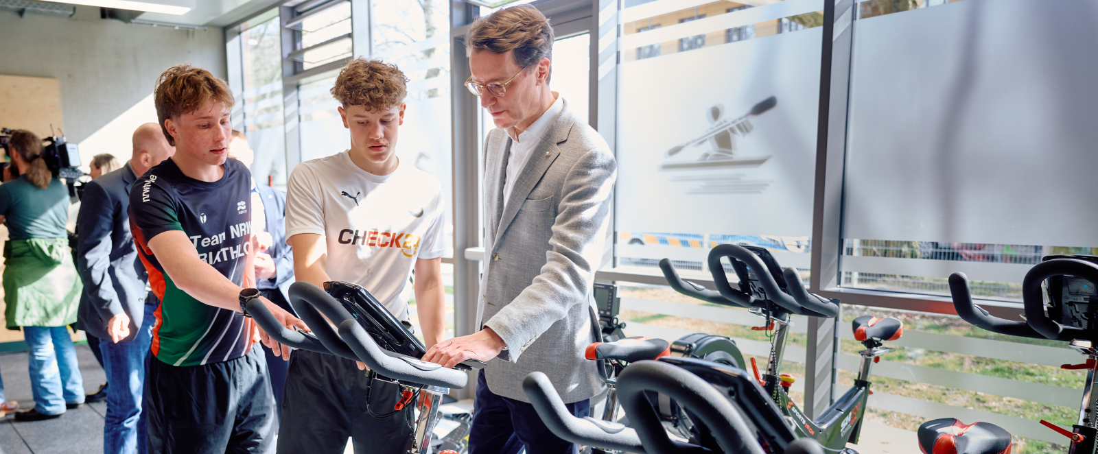 NRW-Ministerpräsident in einem Krafraum im Gespräch mit zwei Jugendlichen