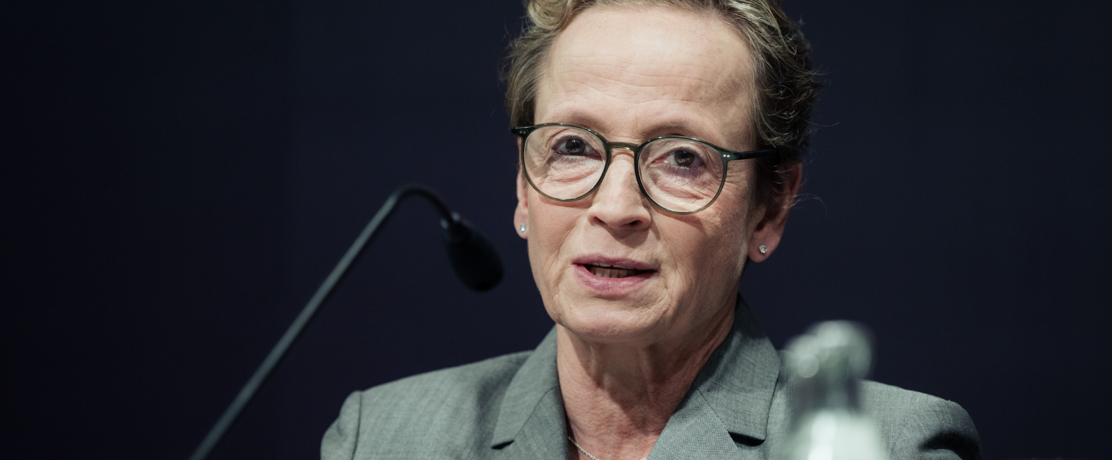 Isabell Werth in einem grünen Anzug vor dunklem Hintergrund