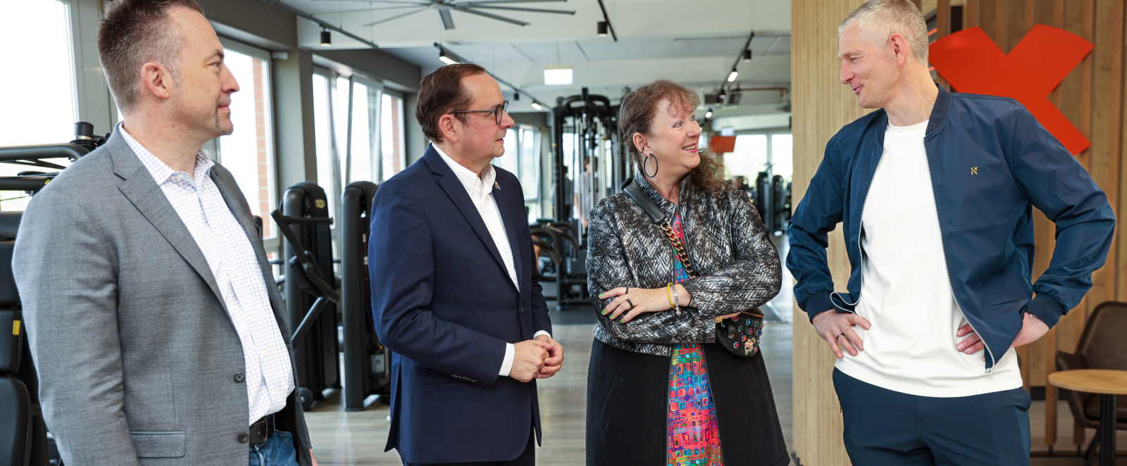 Andrea Milz im Gespräch mit drei Männern, im HIntergrund ein Fitnessstudio