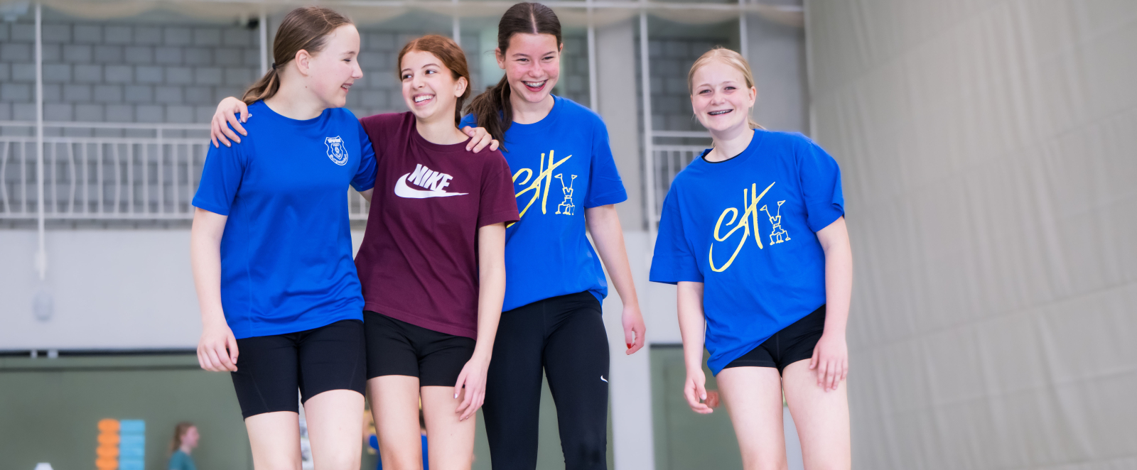 Vier junge Frauen in Sportkleidung in einer Halle