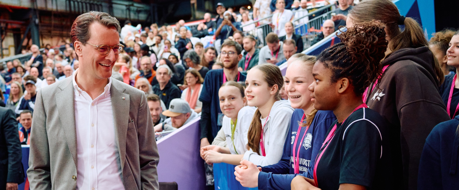 Hendrik Wüst im Gespräch mit jungen Frauen auf Tribünenplätzen 
