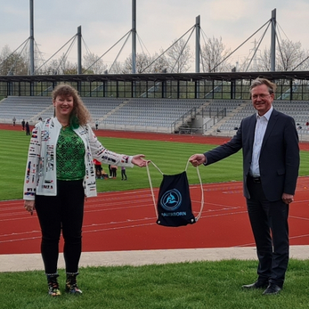 Andrea Milz mit Männern vor Sportanlage