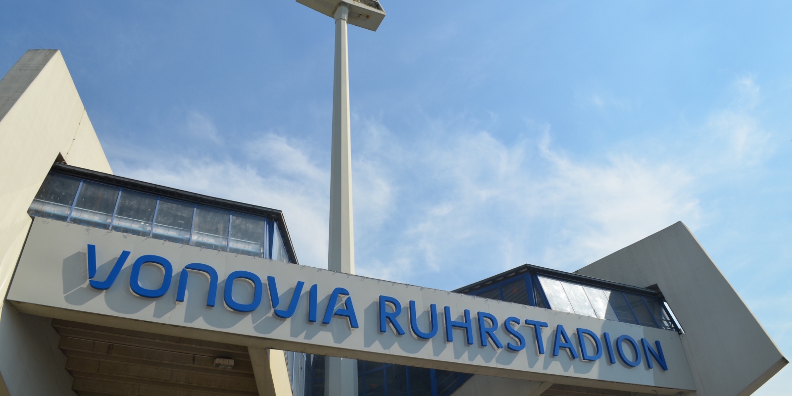 Eingangsbereich des Vonovia Ruhrstadion in Bochum von außen. Der Name "Vonovia Ruhrstadion" prangt in Blau über dem Eingang.