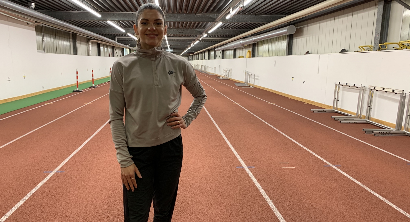 Portrait Pamela Dutkiewicz in einer Sporthalle mit Laufbahn.