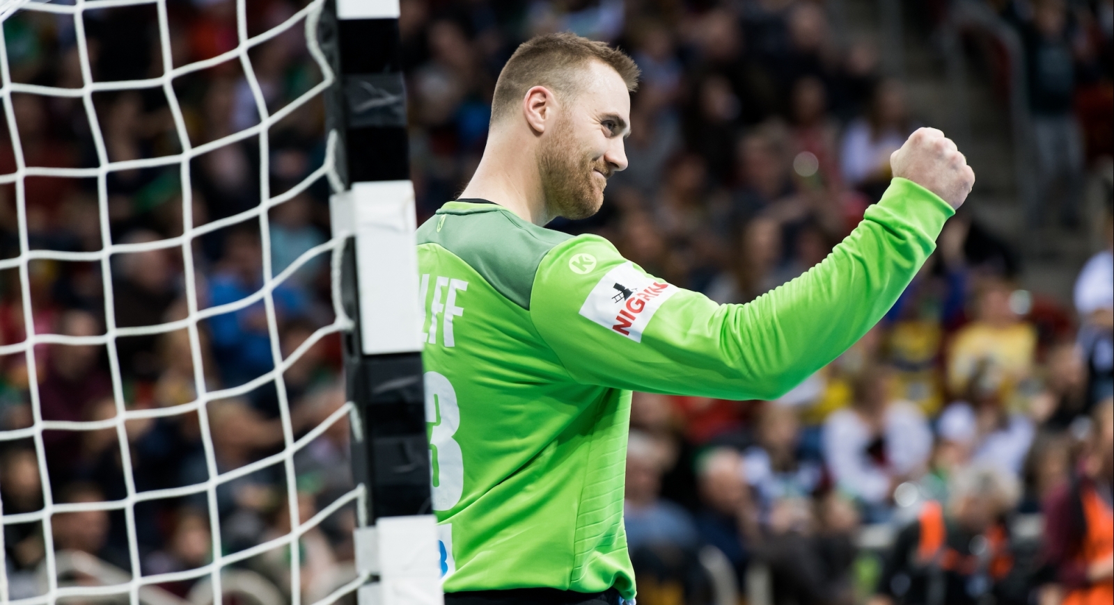 Jubelnder Handballtorwart im grünen Trikot 