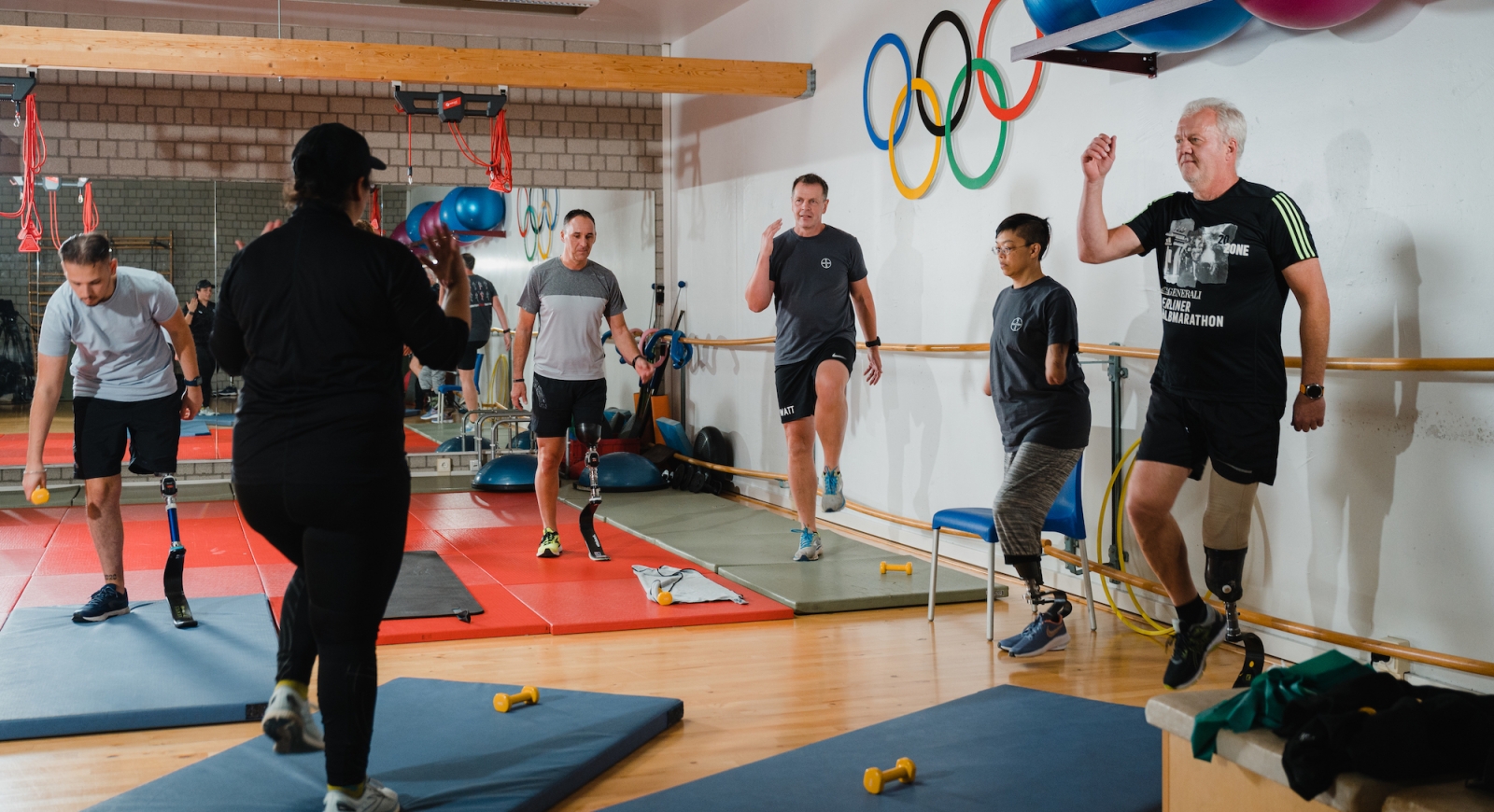 Sechs Teilnehmer eines Fitnessprogramms auf Turn-Matten