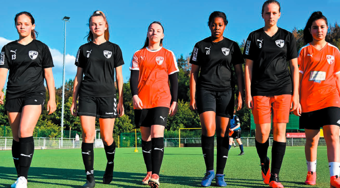 Sechs Fußballerinnen, in einer Reihe auf dem Rasen, in einer Vorwärtsbewegung