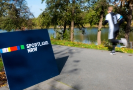 Jogger draußen Sportland.NRW-Schild