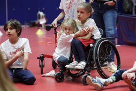 Kinder in einer Halle, ein Kind sitzt in einem Rollstuhl