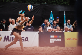 Beachvolleyballspielerin nimmt einen Ball aus der Luft an