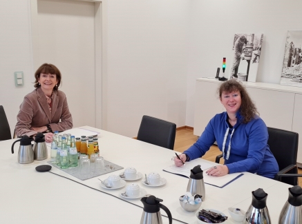 Staatsekretärin Andrea Milz in blauer Strickjacke sitzt mit einer Dame von der Stadt Köln an einem Tisch.