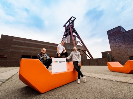 Drei Jugendliche mit Sportland.NRW-Schild auf Zeche Zollverein